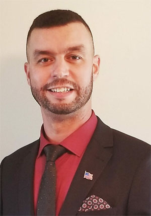 A man in a suit and tie smiling for the camera.